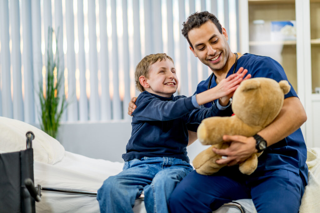 A child with a disability playing with a man holding a teddy bear.