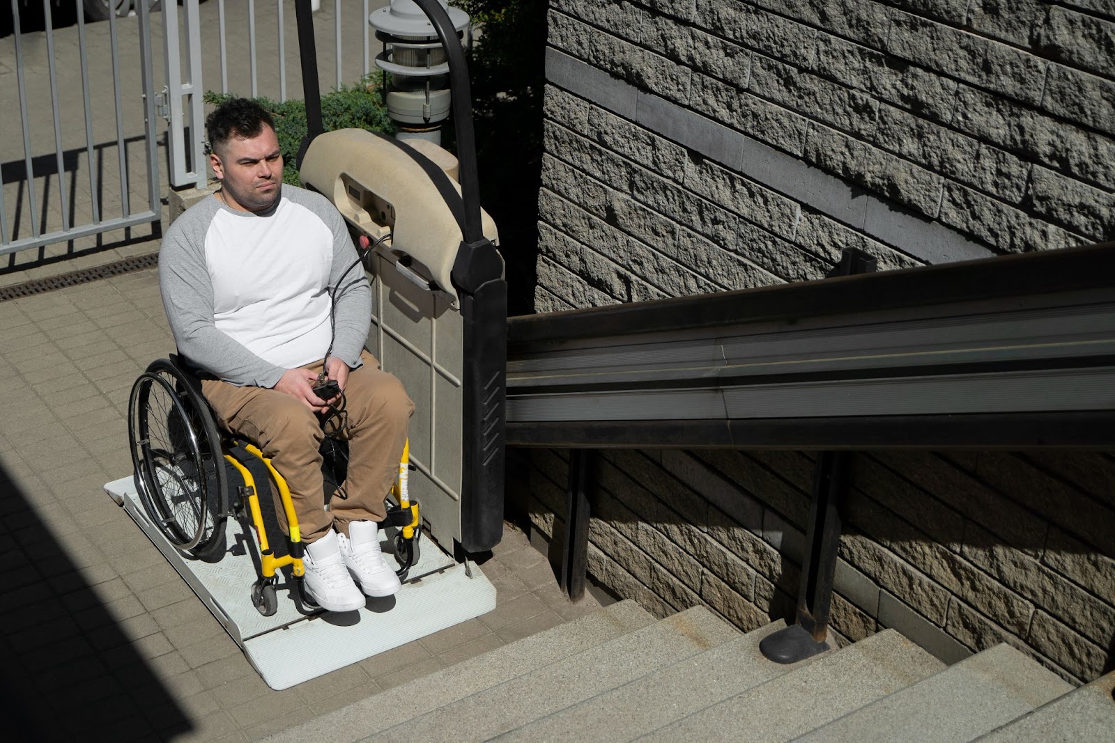 Man in a wheelchair using an outdoor stair lift, showcasing disability adaptive equipment