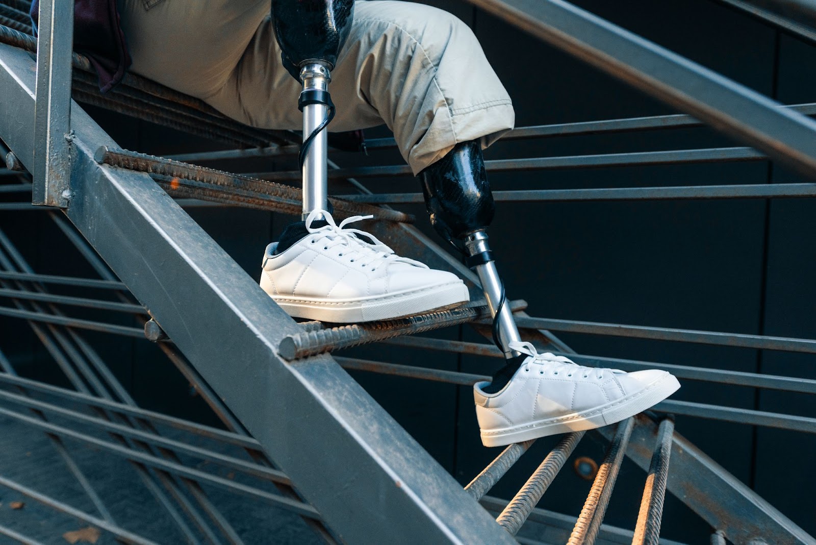 Close-up of prosthetic legs on metal stairs, illustrating disability adaptive equipment